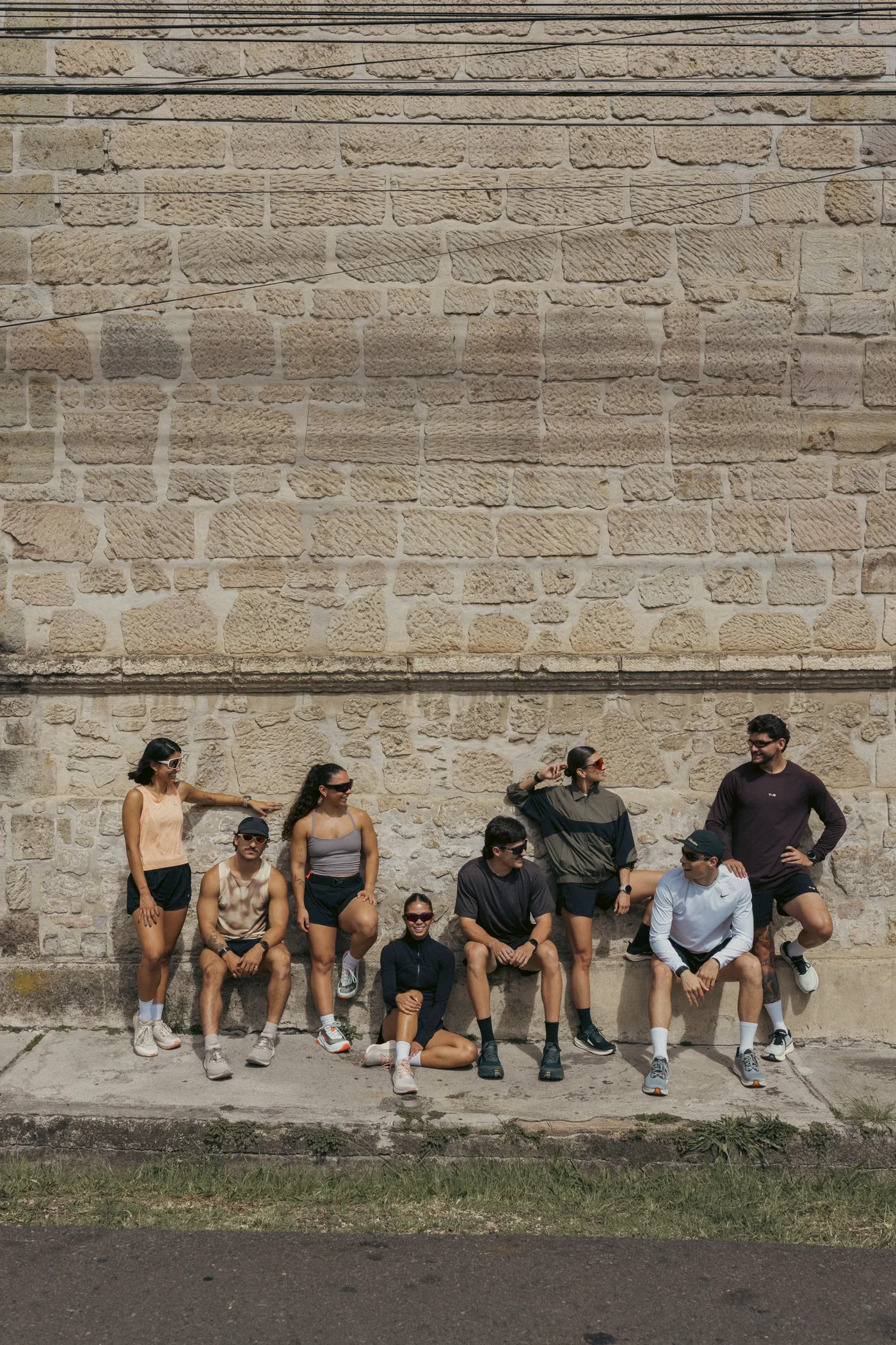 Grupo de corredores sentados frente a un muro de piedra